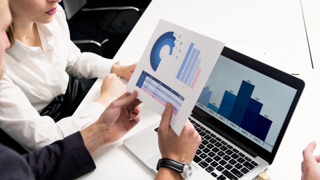 ما هو الـ ERP حقاً؟ ولماذا تفشل 60% من الشركات في تطبيقه؟ (وكيف تكون من الناجحين) Business professionals discussing data charts and graphs in a modern office setting.